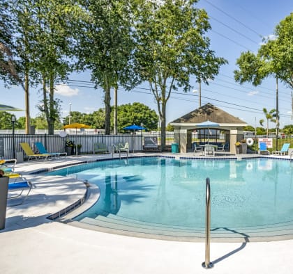 a resort style pool with lounge chairs and a gazebo at Fusion Apartments, Orlando