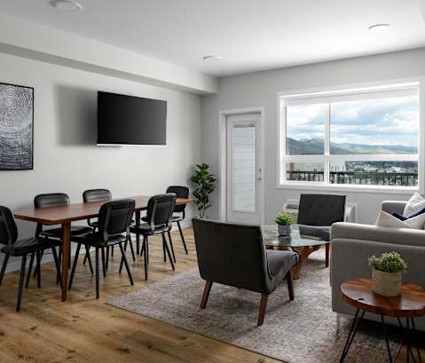 a living and dining area with a table and chairs and a flat screen tv on the wall
