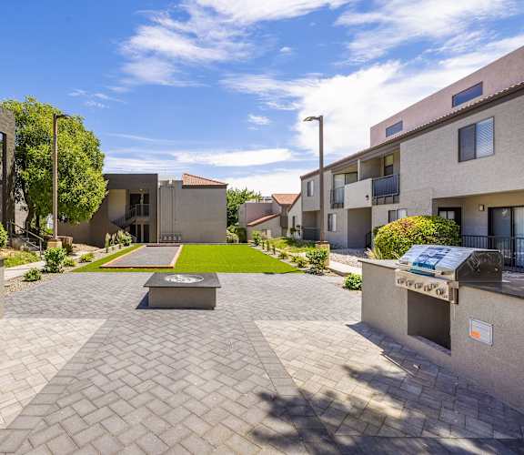 a courtyard between two buildings with a green lawn and benches