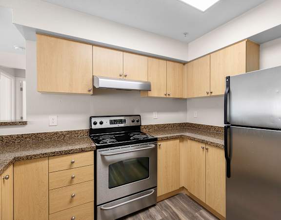 a kitchen with granite countertops and stainless steel appliances at Arabella Apartment Homes in Shoreline, WA