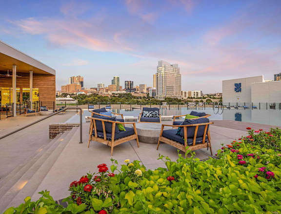 a terrace with a table and chairs with a view of the city in the background