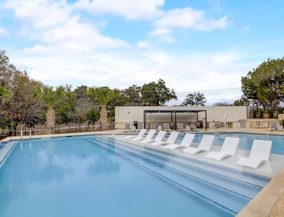 a swimming pool with white lounge chairs next to it