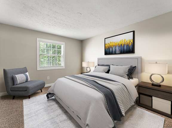 A bedroom with a large bed and a chair at Pines at Lawrenceville Apartments in Decatur, Georgia