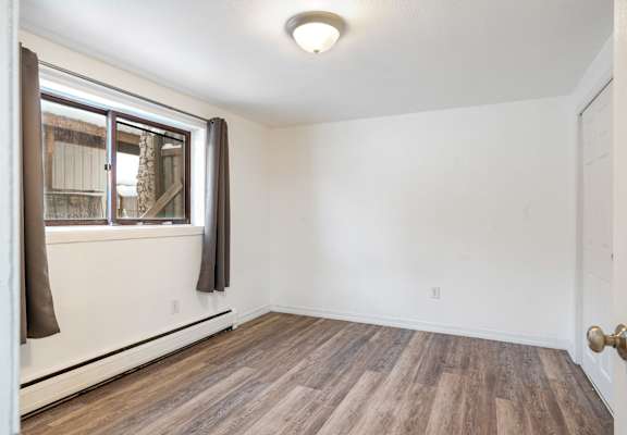 an empty living room with wood floors and a window