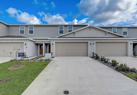 A residential house with a grey roof and two garages.