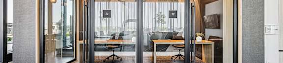 A modern office with glass doors leading to a meeting room.