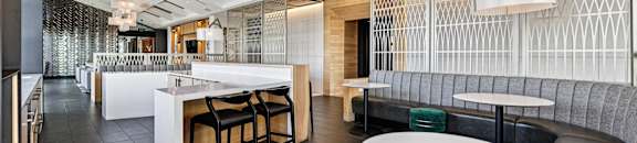 A modern dining area with a white counter and black chairs.