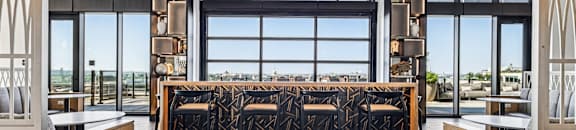 A long table with chairs is in the middle of a room with a large window.