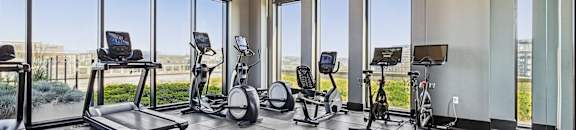A spacious gym with treadmills, stationary bikes, and elliptical machines.