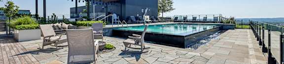 A pool area with a patio and chairs.