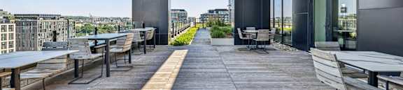 A patio with tables and chairs overlooking a cityscape.