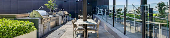 A modern outdoor seating area with a glass railing and a wooden pergola.