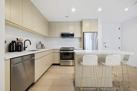 A modern kitchen with a white countertop and stainless steel appliances.