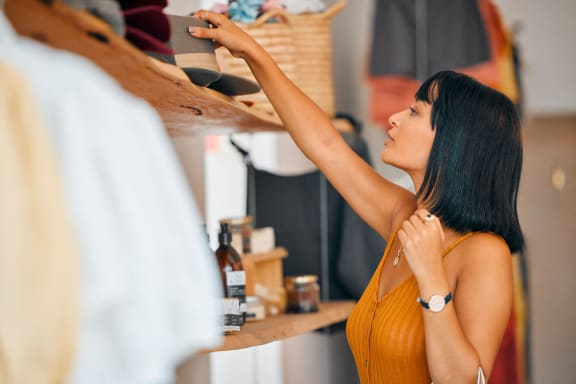 a woman reaching for a shirt on a shelf in a closet at Mediterranean Village Costa Mesa, Costa Mesa, California