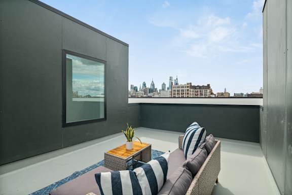 A balcony with a striped couch and a table with a vase of flowers.