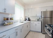 Thumbnail 18 of 22 - A modern kitchen with white cabinets and stainless steel appliances.