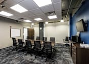 Thumbnail 13 of 14 - a conference room with a table and chairs and a tv at 100 South Apartments, Buffalo, NY 14202