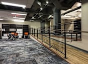 Thumbnail 4 of 14 - a room with a railing and a table and chairs in a library at 100 South Apartments, Buffalo, New York