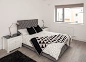 Thumbnail 3 of 5 - a bedroom with a bed and a black and white comforter