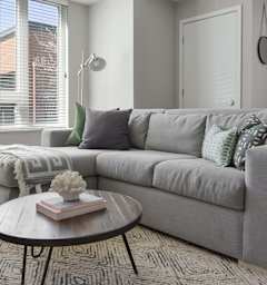 A grey couch with a round table in front of it.