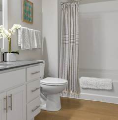 A white toilet sits in a bathroom next to a bathtub.