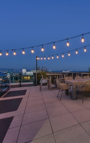 a rooftop terrace with tables and chairs and string lights