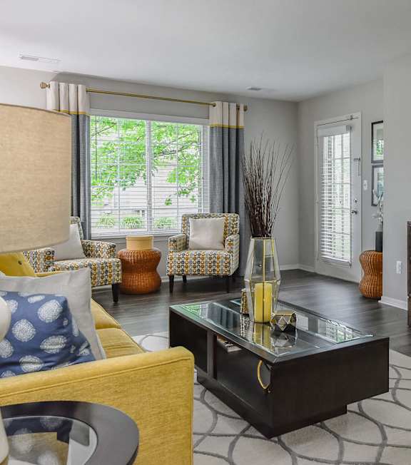 A living room with a yellow chair and a black coffee table.