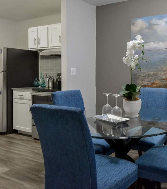 A dining room with a glass table and blue chairs.