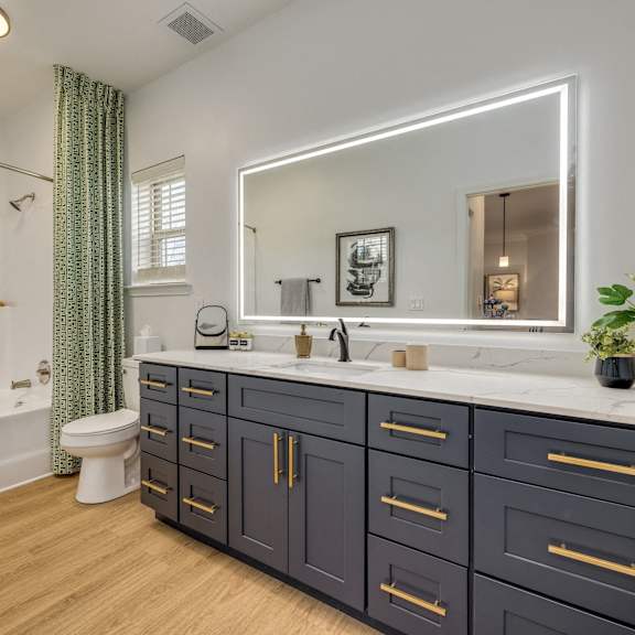 A bathroom with a white tub, sink, and a mirror.
