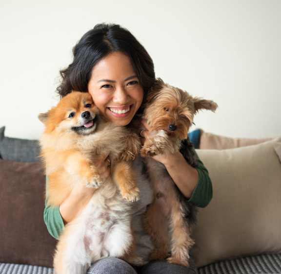 A woman is holding two small dogs in her arms.