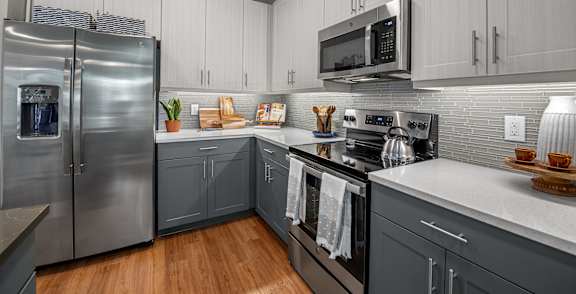 A modern kitchen with a stainless steel refrigerator and a microwave above the stove.