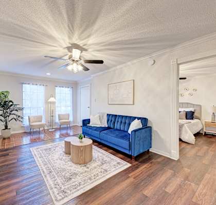 A living room with a blue couch and a flat screen TV mounted on the wall.