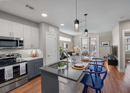 A modern kitchen with a large island and blue chairs.