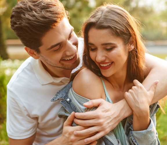 a man and woman hugging in a park