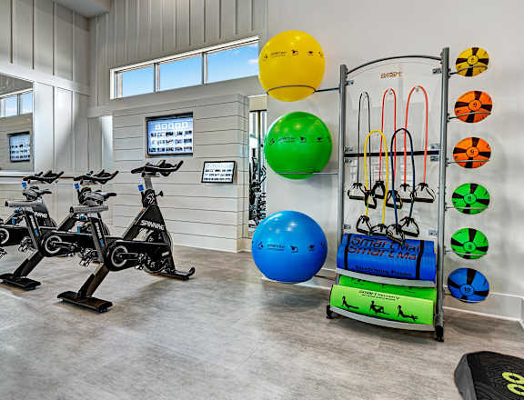 A gym with exercise equipment and a wall of windows.