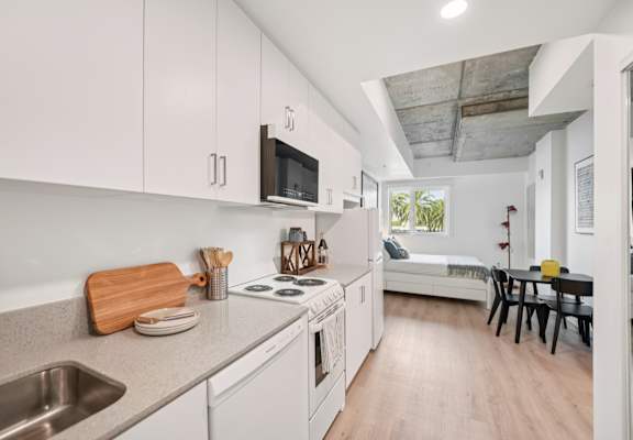 A kitchen with white cabinets and a wooden cutting board on the counter.