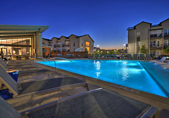 A swimming pool at a resort with sun loungers and a building in the background.
