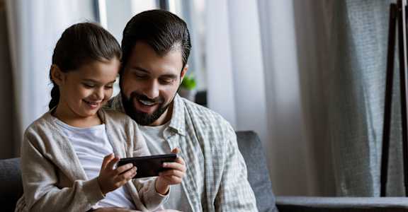a man and woman sitting on a couch looking at a cell phone