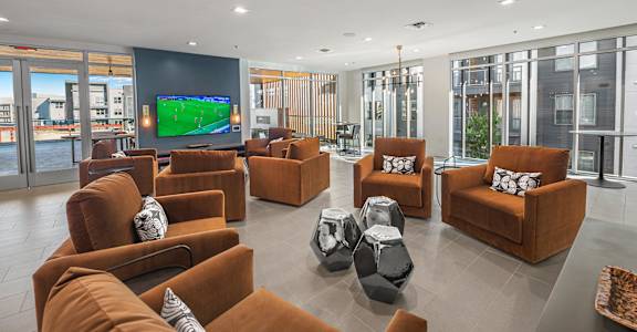 A living room with a television and multiple chairs.