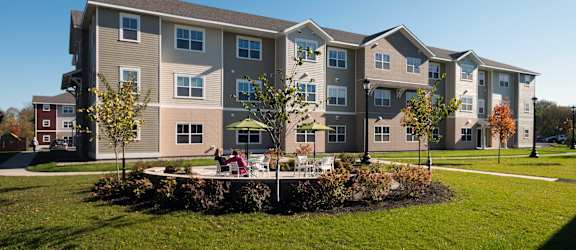 A large apartment complex with a grassy area in front at Meadows Senior Living Apartments, New Hartford, NY, 13413