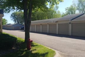 Detached garages with gray doors and an extensive driveway.