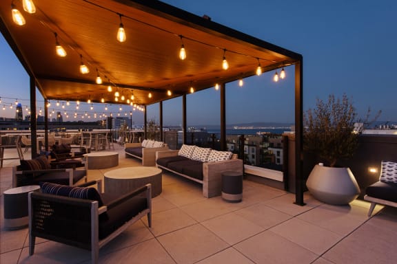 a roof top patio with chairs and tables and lights