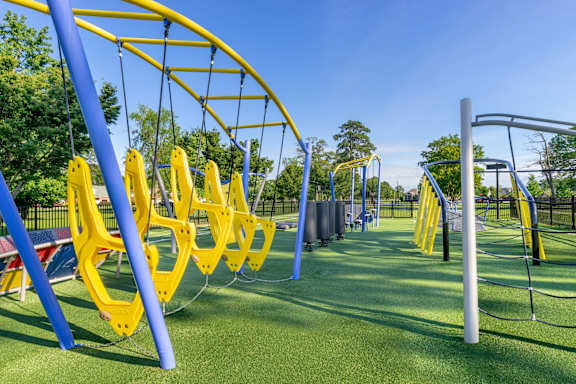 A playground with blue and yellow swings.