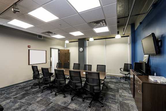 a conference room with a table and chairs and a tv at 100 South Apartments, Buffalo, NY 14202