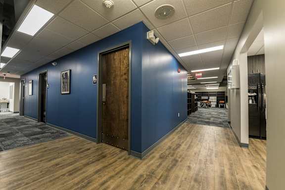a hallway with a blue wall and wooden floors and doors at 100 South Apartments, Buffalo, NY 14202