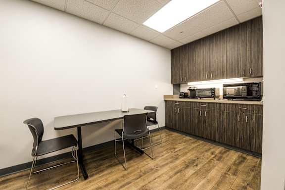 a room with a table and chairs and a counter with a microwave at 100 South Apartments, NY 14202