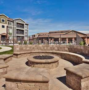A fire pit sits in the middle of a stone patio.