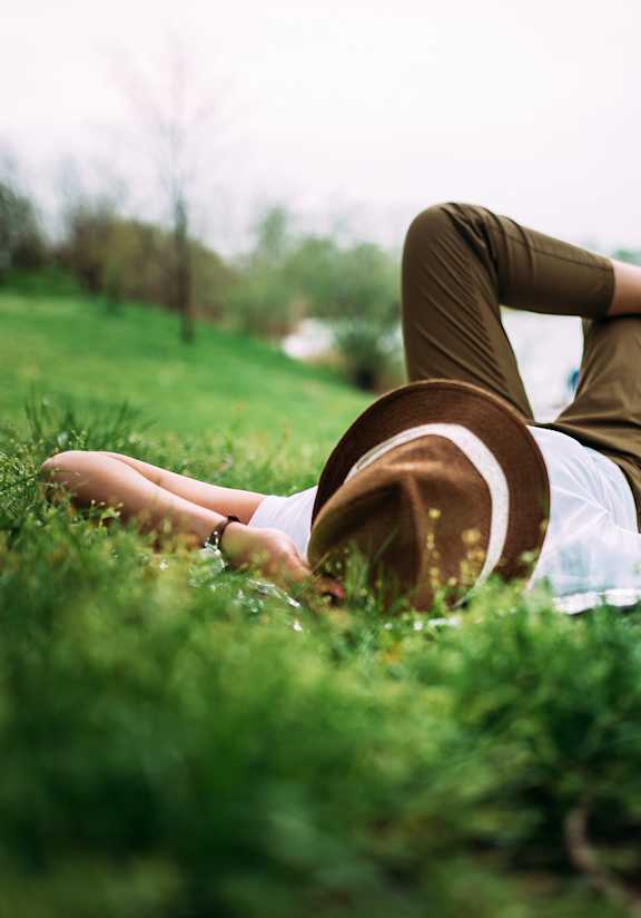 A person is lying on the grass and using a tablet.