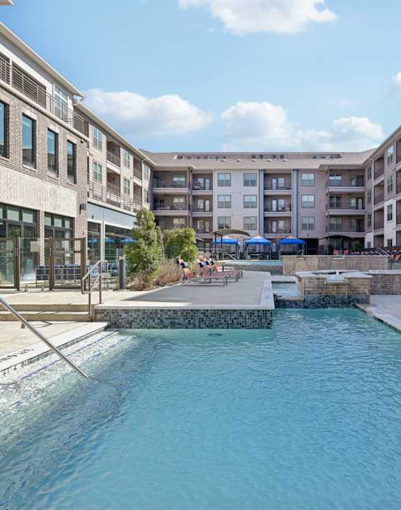 A swimming pool in a residential area surrounded by apartment buildings.