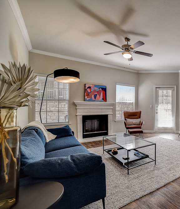 A living room with a fireplace, a blue couch, and a dining table.